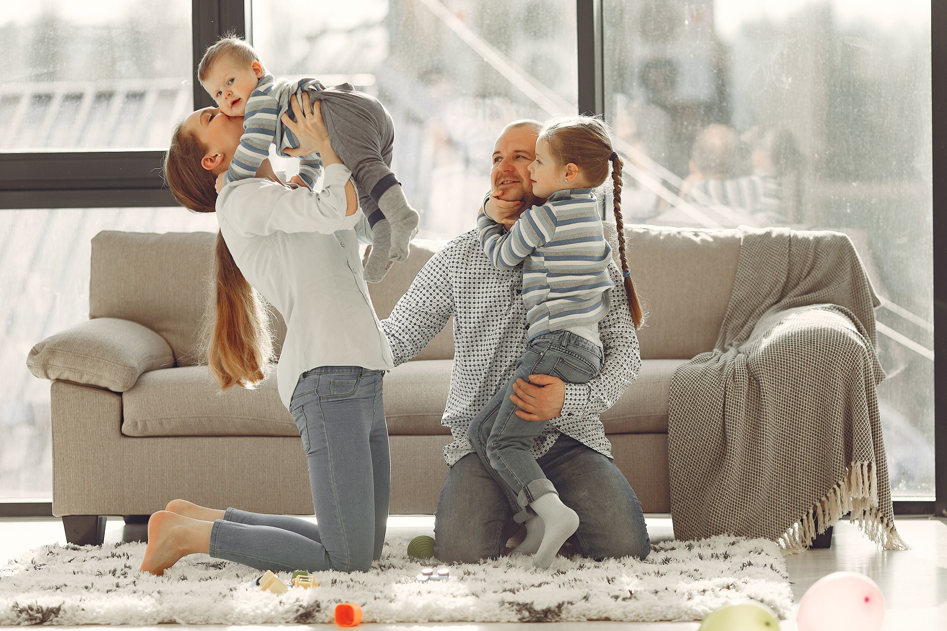 Famiglia felice si abbraccia sul divano di casa
